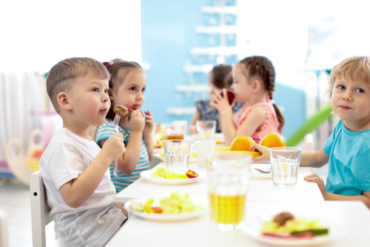 kids have a lunch in daycare centre. children eating healthy food in kindergarten